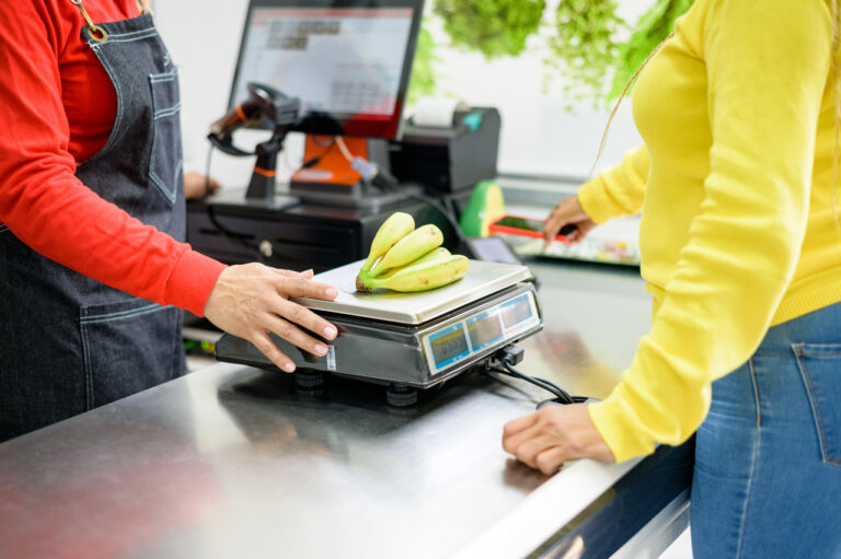 Crop seller weighing bananas for customer
